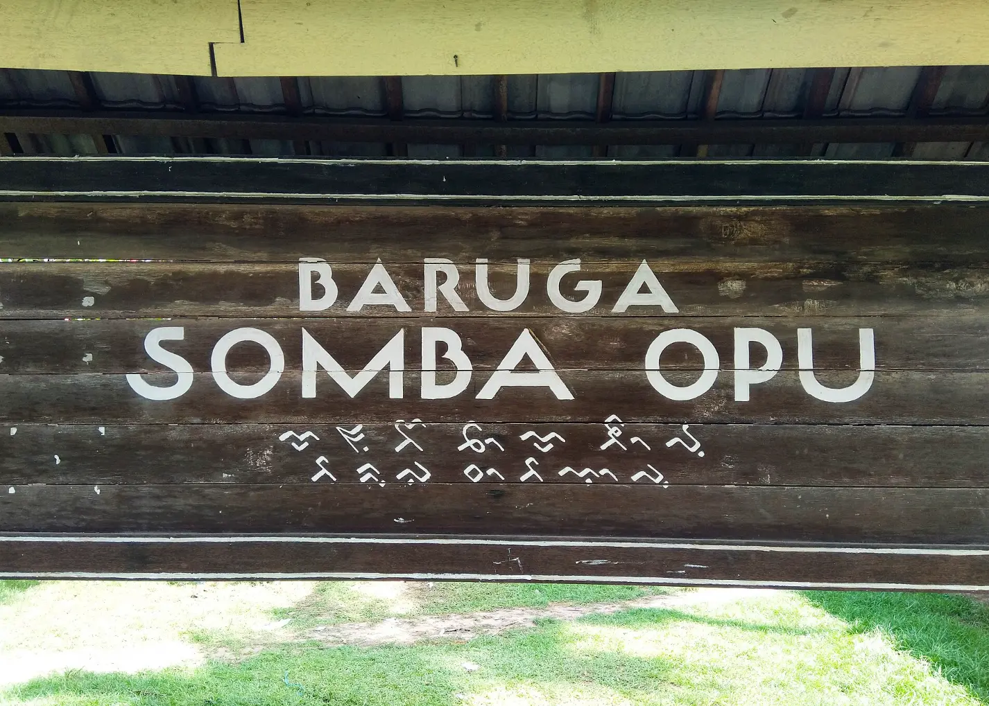 Papan nama Baruga Somba Opu, Gowa, dengan aksara Lontara (baris paling bawah) dan aksara Makassar (baris kedua dari bawah)
